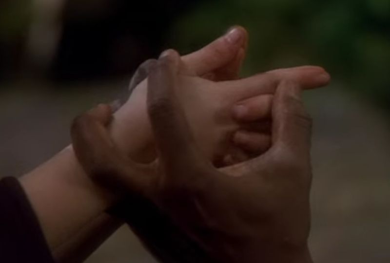 Picture shows Tuvok's helping the girl get the right hand position. Her palms are together, and all her fingers are intertwined, except the index fingers, which are pointed outwards, with the fingertips touching.